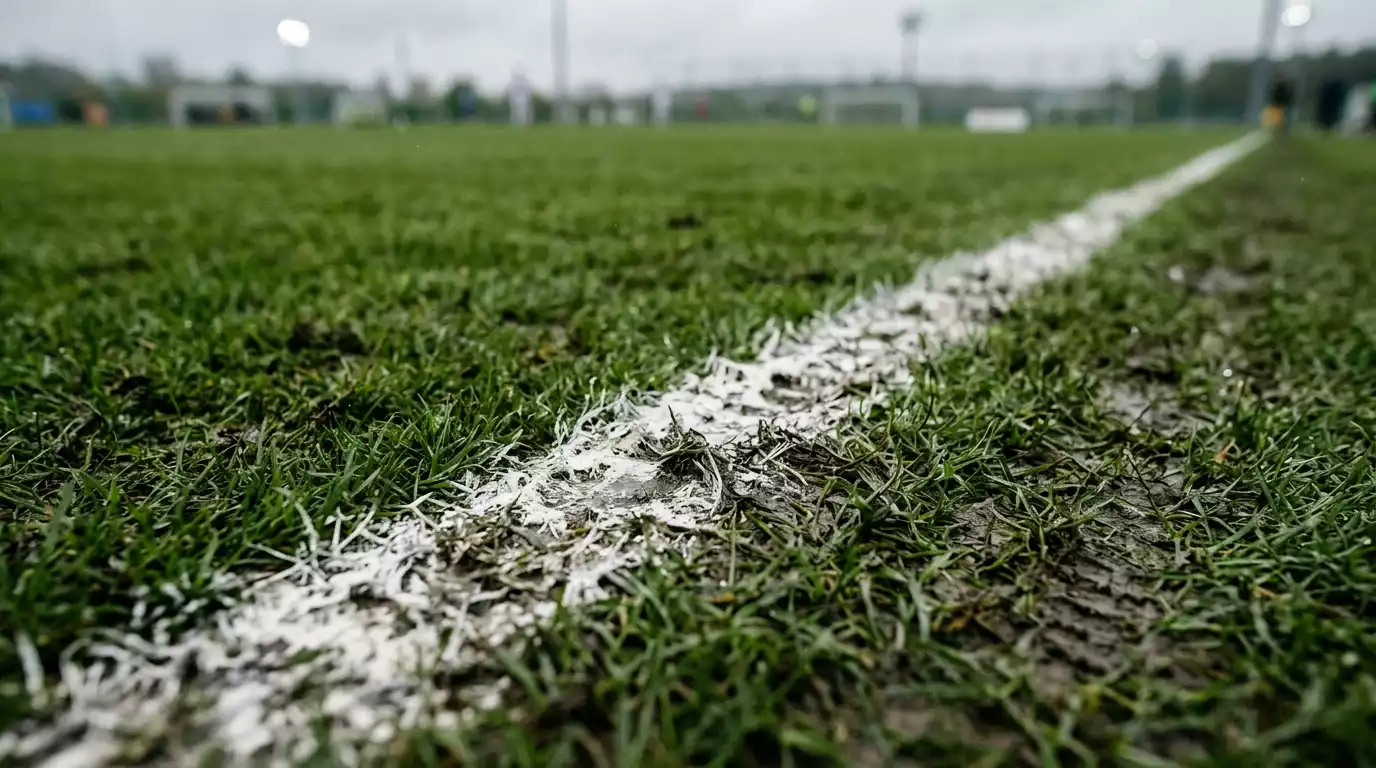 Línea de cal del área de fútbol vista de cerca con césped desgastado